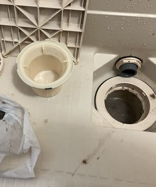 排水溝に詰まった髪の毛の除去作業