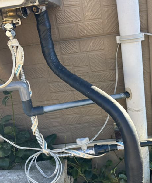 水道管の保温材を撤去して電熱線を取り付け作業